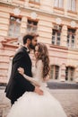 Happy newlywed couple hugging and kissing in old European town street, gorgeous bride in white wedding dress together with Royalty Free Stock Photo