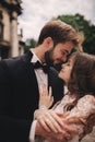 Happy newlywed couple hugging and kissing in old European town street, gorgeous bride in white wedding dress together with Royalty Free Stock Photo