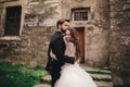 Happy newlywed couple hugging and kissing in old European town street, gorgeous bride in white wedding dress together with Royalty Free Stock Photo