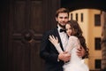 Happy newlywed couple hugging and kissing in old European town street, gorgeous bride in white wedding dress together with Royalty Free Stock Photo