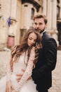 Happy newlywed couple hugging and kissing in old European town street, gorgeous bride in white wedding dress together Royalty Free Stock Photo
