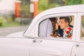 Happy newlywed couple kissing on a backseat of vintage car Royalty Free Stock Photo