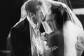 Happy newlywed couple kissing bride and handsome groom under veil b&w Royalty Free Stock Photo