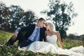 Happy newlywed couple relaxing & posing in a field at sunset Royalty Free Stock Photo