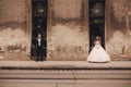 Happy newlywed couple on a walk in old European town street, gorgeous bride in white wedding dress together with handsome groom Royalty Free Stock Photo