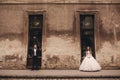 Happy newlywed couple on a walk in old European town street, gorgeous bride in white wedding dress together with handsome groom Royalty Free Stock Photo