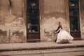 Happy newlywed couple on a walk in old European town street, gorgeous bride in white wedding dress together with handsome groom Royalty Free Stock Photo