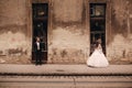 Happy newlywed couple on a walk in old European town street, gorgeous bride in white wedding dress together with handsome groom Royalty Free Stock Photo