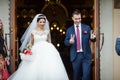 Happy newlywed romantic couple coming out of church after wedding ceremony with a candy basket Royalty Free Stock Photo