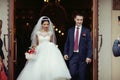 Happy newlywed romantic couple coming out of church after wedding ceremony with a candy basket Royalty Free Stock Photo