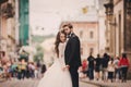 Happy newlyweds couple on a walk in old European town street, gorgeous bride in white wedding dress together with handsome groom Royalty Free Stock Photo