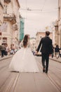 Happy newlyweds couple on a walk in old European town street, gorgeous bride in white wedding dress together with handsome groom. Royalty Free Stock Photo