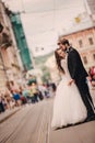 Happy newlyweds couple on a walk in old European town street, gorgeous bride in white wedding dress together with handsome groom Royalty Free Stock Photo