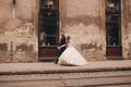 Happy newlyweds couple on a walk in old European town street, gorgeous bride in white wedding dress together with handsome groom Royalty Free Stock Photo