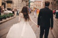 Happy newlyweds couple on a walk in old European town street, gorgeous bride in white wedding dress together with handsome groom. Royalty Free Stock Photo