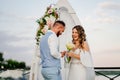 happy newlyweds exchange rings. beautiful wedding ceremony by water on dock.