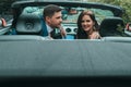 Happy newlyweds go to the celebration in a red car with an open top. Wedding Concept Royalty Free Stock Photo