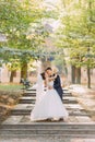 Happy newlyweds are hugging in the park during the sunny day. Full-length view. Royalty Free Stock Photo
