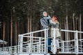 Happy newlyweds stand on a pier on a snowy riverbank in the winter morning Royalty Free Stock Photo