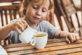 Happy nice boy pours honey into the tea in summer green garden. Royalty Free Stock Photo