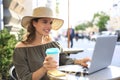 Happy nice woman working on laptop in street cafe, holding paper cup Royalty Free Stock Photo