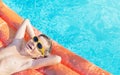 Happy nine years old caucasian child boy in yellow sunglasses having fun on inflatable ring air mattress in swimming pool.