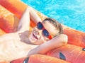 Happy nine years old child boy in red sunglasses playing with inflatable ring air mattress in swimming pool. Caucasian kid. Royalty Free Stock Photo