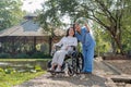 Happy nurse and elderly woman sitting in wheelchair enjoying outdoor. Beautiful nurse with senior woman in wheelchair at Royalty Free Stock Photo