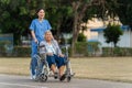 happy nurse take care and pushing senior woman in wheelchair at park, friendly caregiver Royalty Free Stock Photo