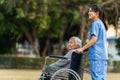 happy nurse take care and pushing senior woman in wheelchair at park, friendly caregiver Royalty Free Stock Photo