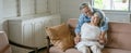 happy old asian husband take care and embracing elderly wife sitting on sofa in living room at home . Lovely asia senior couple in Royalty Free Stock Photo