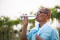 A happy old asian man is drinking water at park with sunlight. Healthcare and senior sports concept Royalty Free Stock Photo