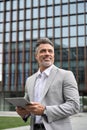 Happy old businessman wearing suit using tablet looking away. Vertical. Royalty Free Stock Photo