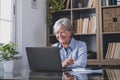 Happy old caucasian businesswoman smiling working online watching webinar podcast on laptop and learning education course Royalty Free Stock Photo