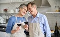 Happy old couple bonding, drinking wine standing in kitchen cooking at home. Royalty Free Stock Photo