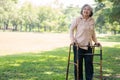 Happy old elderly Asian woman uses a walker for osteoarthritis rehabilitation physiotherapy in park. Concept of happy retirement Royalty Free Stock Photo