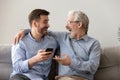 Happy old father and son having fun, using phone together Royalty Free Stock Photo