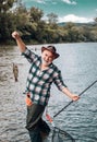 Happy old fisherman caught a trout fish. Portrait of cheerful smiling senior man fishing. Grandfather with catch fish. Royalty Free Stock Photo