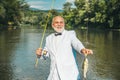 Happy old fisherman caught a trout fish. Portrait of cheerful smiling senior man fishing. Grandfather with catch fish Royalty Free Stock Photo