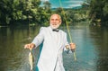 Happy old fisherman caught a trout fish. Portrait of cheerful smiling senior man fishing. Grandfather with catch fish