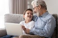 Happy old grandfather and grandson laughing using laptop on sofa Royalty Free Stock Photo