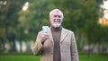 Happy old man holding dollar bills in hand, retirement savings, pension fund