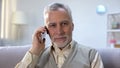 Happy old man receiving good news on cellphone, cheap mobile provider, roaming Royalty Free Stock Photo
