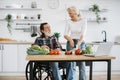 Happy old married man in wheelchair and wife prepare healthy salad. Royalty Free Stock Photo