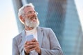 Happy old professional business man holding phone using smartphone outdoors. Royalty Free Stock Photo