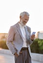 Happy old professional business man holding using phone outdoor, vertical. Royalty Free Stock Photo