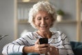 Happy old senior grey-haired woman using mobile applications. Royalty Free Stock Photo