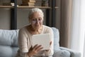 Happy old senior woman in glasses using digital touchpad gadget. Royalty Free Stock Photo