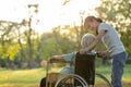 Happy old senior woman in wheelchair with granddaughter walking outdoor at park,smiling child girl and elderly grandmother rest Royalty Free Stock Photo