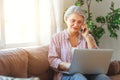 Happy old woman senior working at computer laptop at home